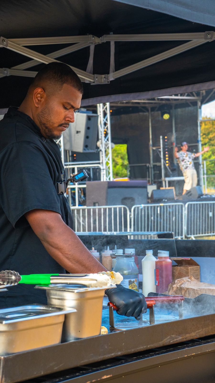 Chef smashing burgers on the griddle with a live stage behind