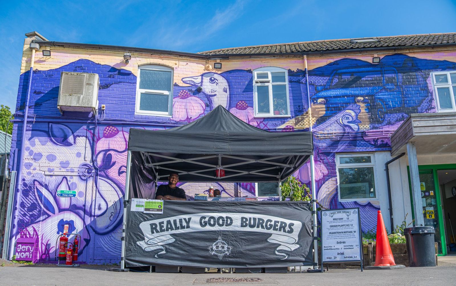Really Good Burgers gazebo in front of a purple painted mural
